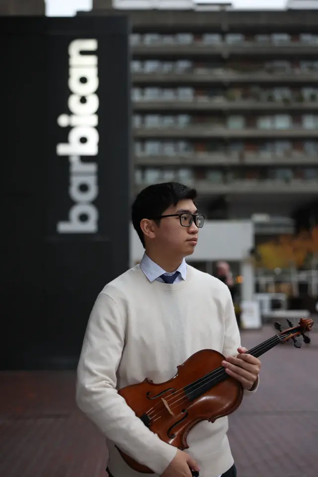 Sean Lee holding his viola outside the Barbican